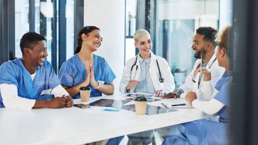 Healthcare workers seated at a table, talking and smiling