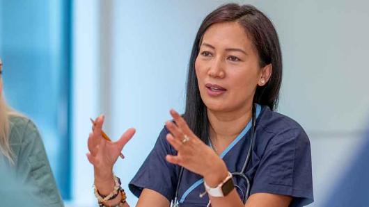 A health care worker sitting at a table talking to colleagues.