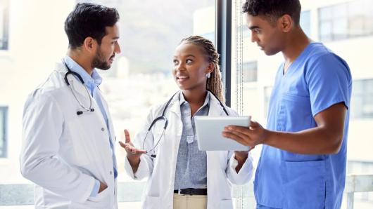 Three health care workers standing in front of a window conversing