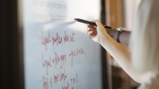 Participant writing on digital whiteboard during brainstorming session.