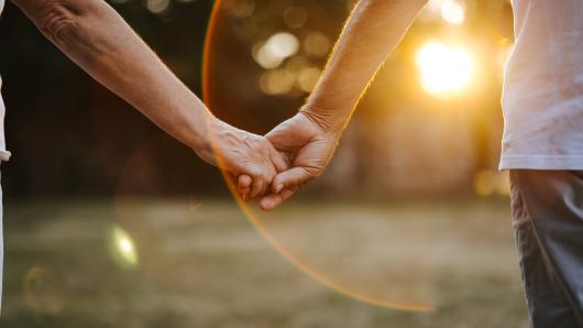 Romantic senior couple walking in nature at sunset - stock photo