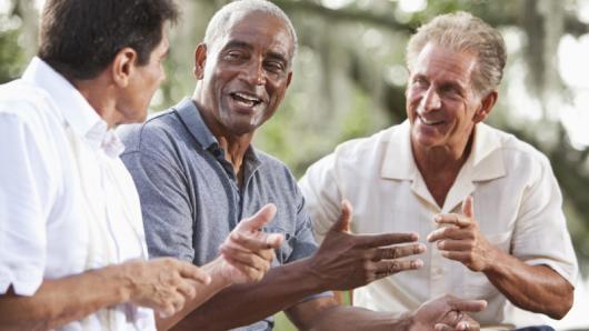 Three men talking and smiling together. 