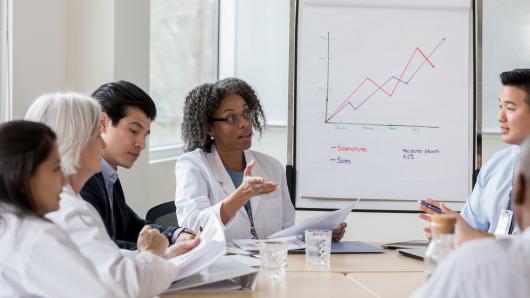 Hospital leaders sit around conference table in discussion