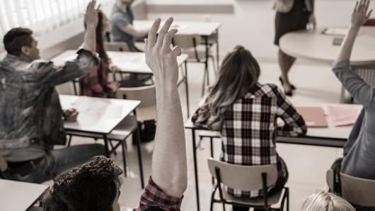 Students raising their hands in a classroom