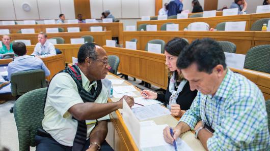 A diverse trio executives sitting in a classroom discussing a case