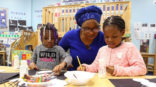 Teacher working with two kids on art project.